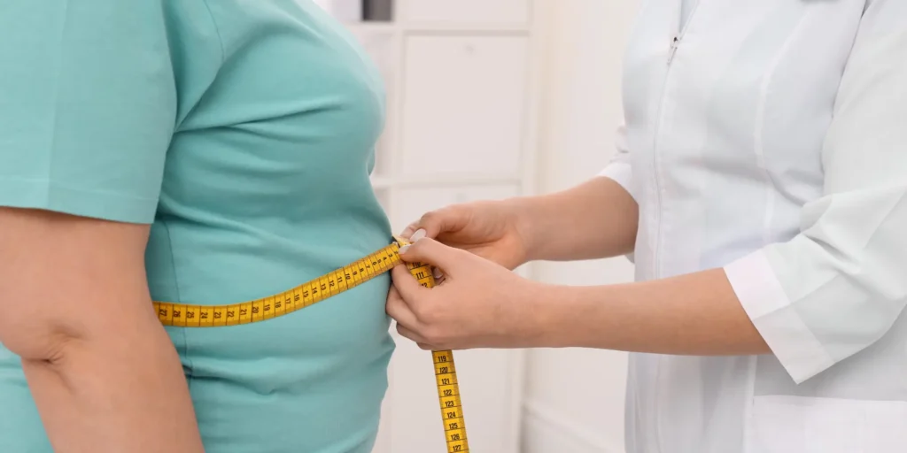 Clinician measuring patient’s waist during GLP-1 weight loss consultation.